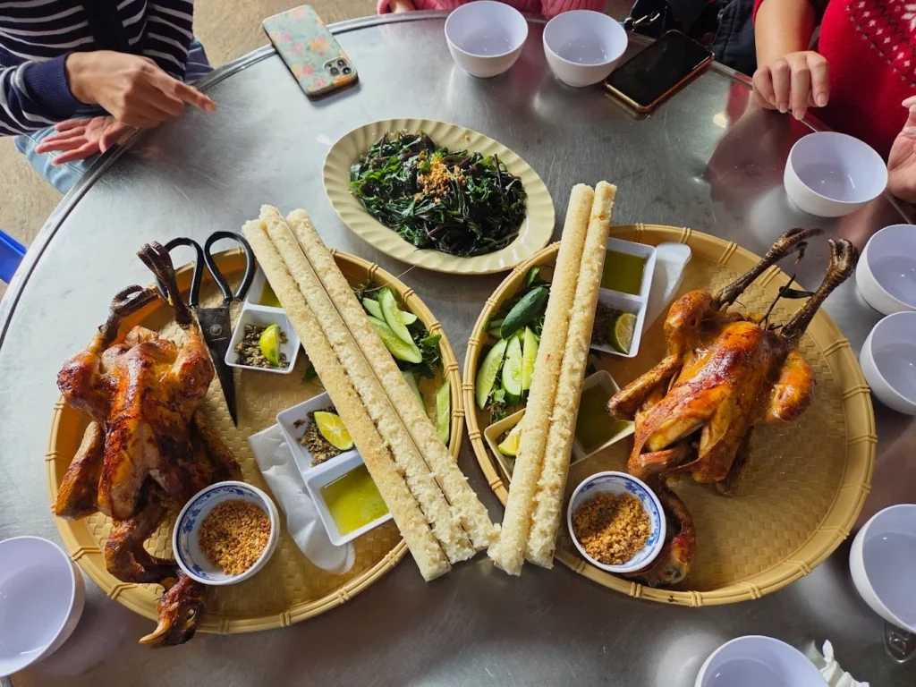 Bàn ăn với món gà nướng mật ong và cơm lam ống tre đặc sản Măng Đen gần khu vực hồ Đăk Ke.