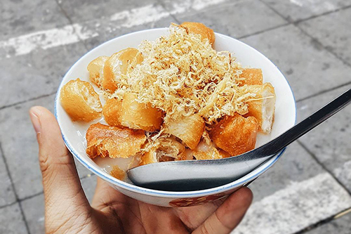 Cô Là - Lý Quốc Sư  Đối với những người yêu thích món ăn này, quán cháo cô Là là địa chỉ quen thuộc. Trước đây, cô bán ở ngõ Huyện, sau này dời về ngã tư Lý Quốc Sư - Hàng Bông. Bát cháo lúc nào cũng nóng hổi được nấu bằng nước hầm xương nên có mùi thơm và vị ngọt. Trong bát còn có thêm chút thịt xào, ruốc (chà bông) và sườn sụn. Một tô cháo quẩy có giá 15.000 đồng, thêm ruốc là 20.000 đồng, thêm sườn sụn là 25.000 đồng. Cô Là bán vào 2 khung giờ: 7h - 11h và 14h - 18h. Ảnh: Phong Ng.
